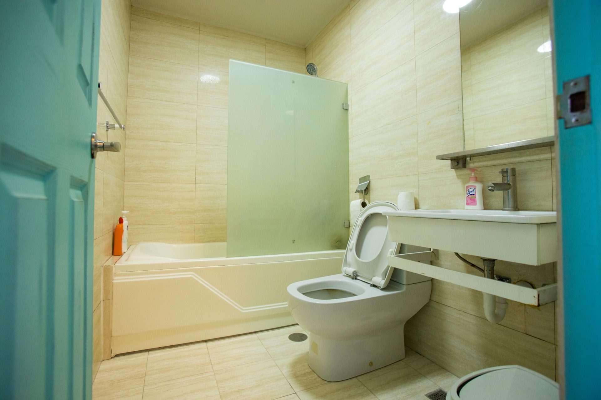 Apartment 1809 tiled bathroom with a bathtub and frosted-glass shower screen