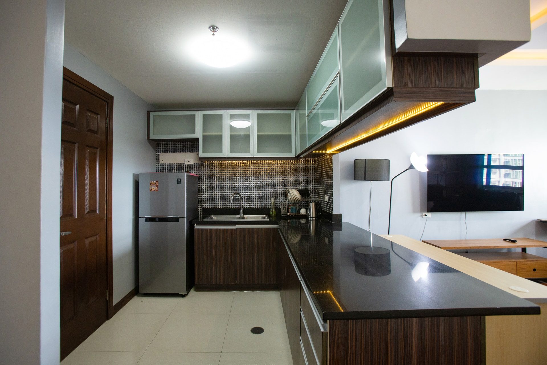 Apartment 1809 kitchen with dark counters, frosted-glass upper cabinets and a refrigerator