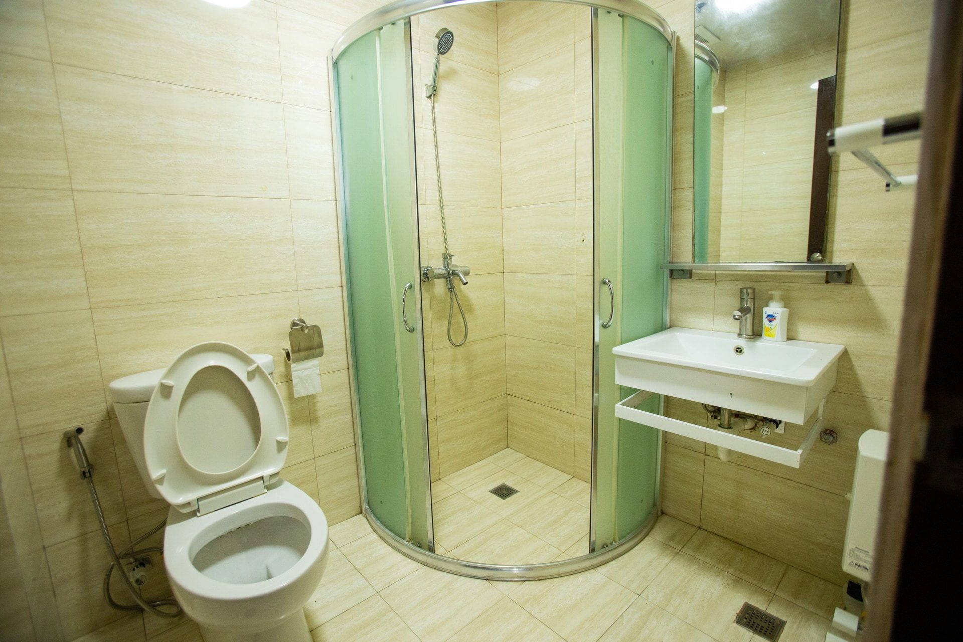 Apartment 1809 tiled shower room with a curved glass enclosure