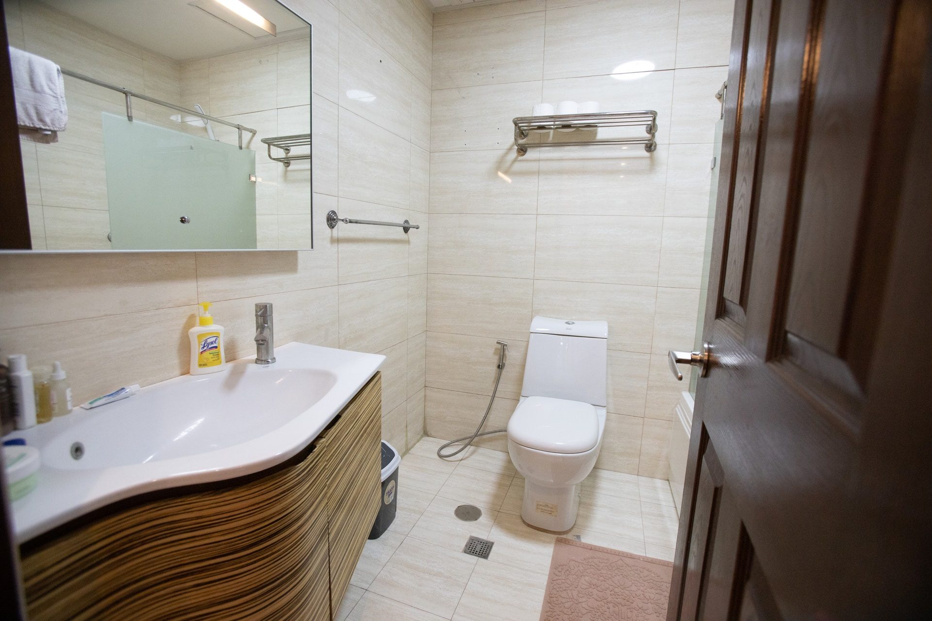 Apartment 1810 bathroom with a curved vanity, wide mirror and tiled walls