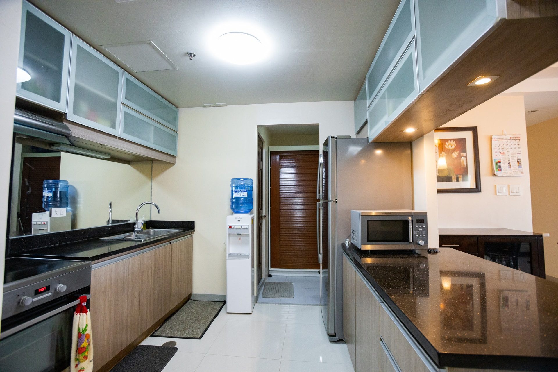Apartment 1810 kitchen with black countertops, wood-finished cabinetry and built-in cooking appliances